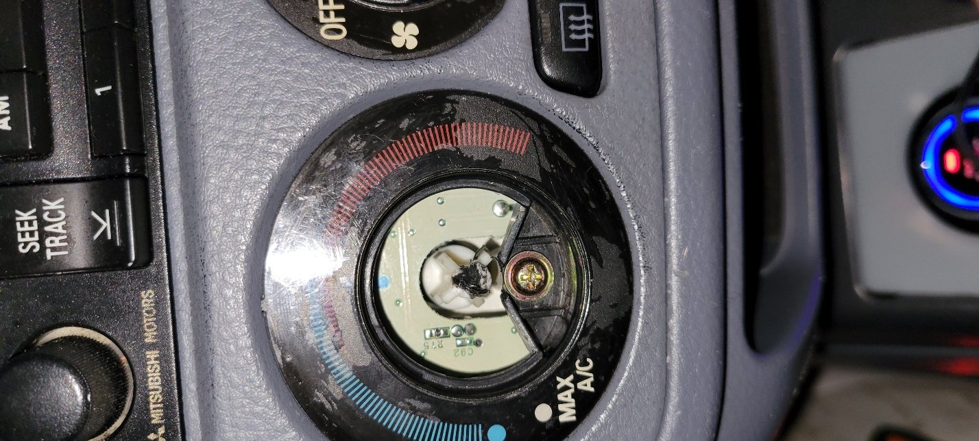 The broken temperature control knob on the Lancer's dashboard, cracked and glued unsuccessfully.
