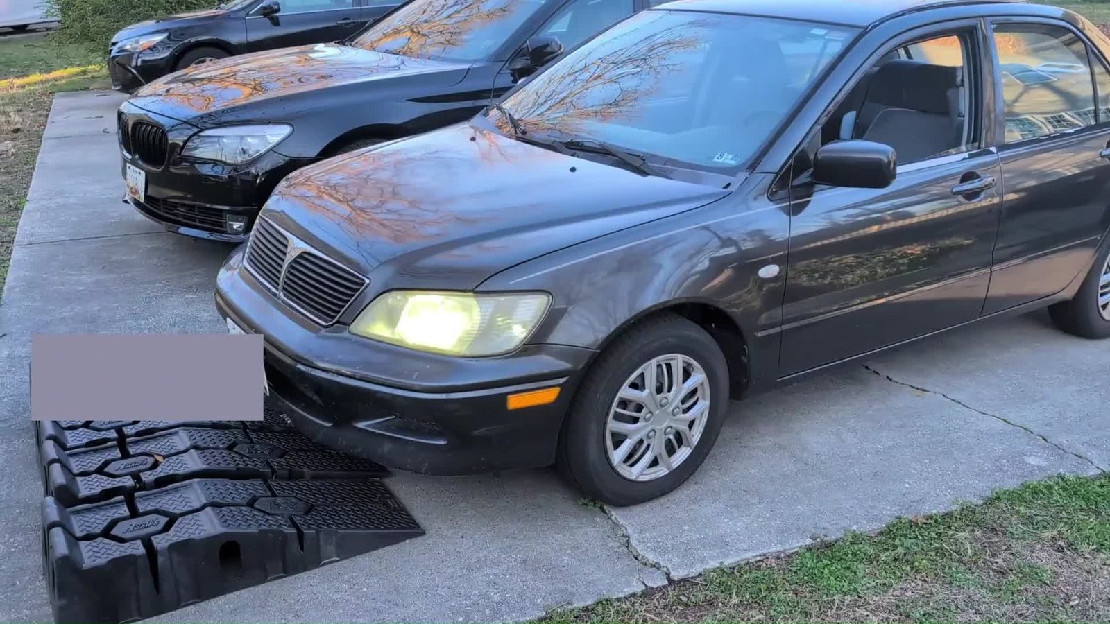 The Lancer in the driveway with its headlights on, from the Part 1 intro.